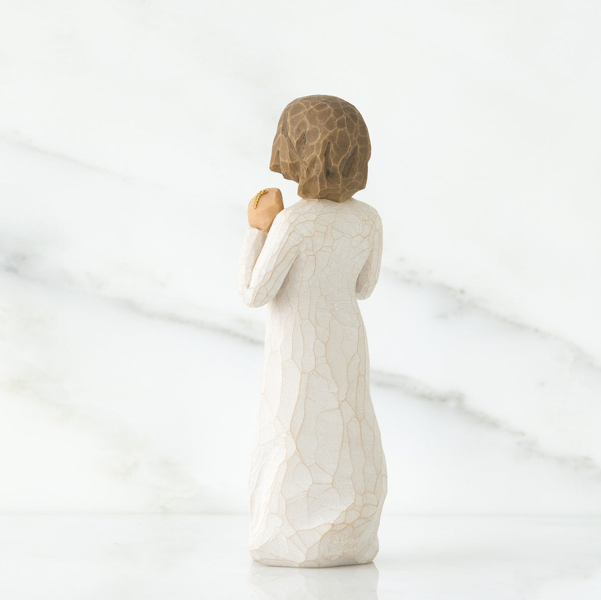 Back view of brunette girl figurine in white dress