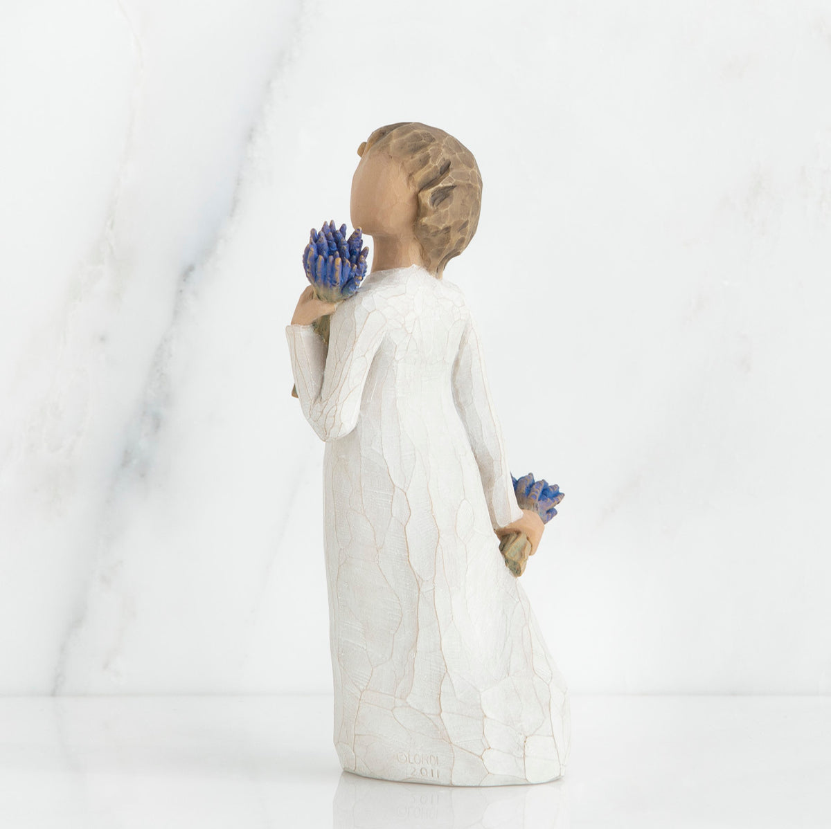 Brunette girl figurine in white dress holding blue flowers