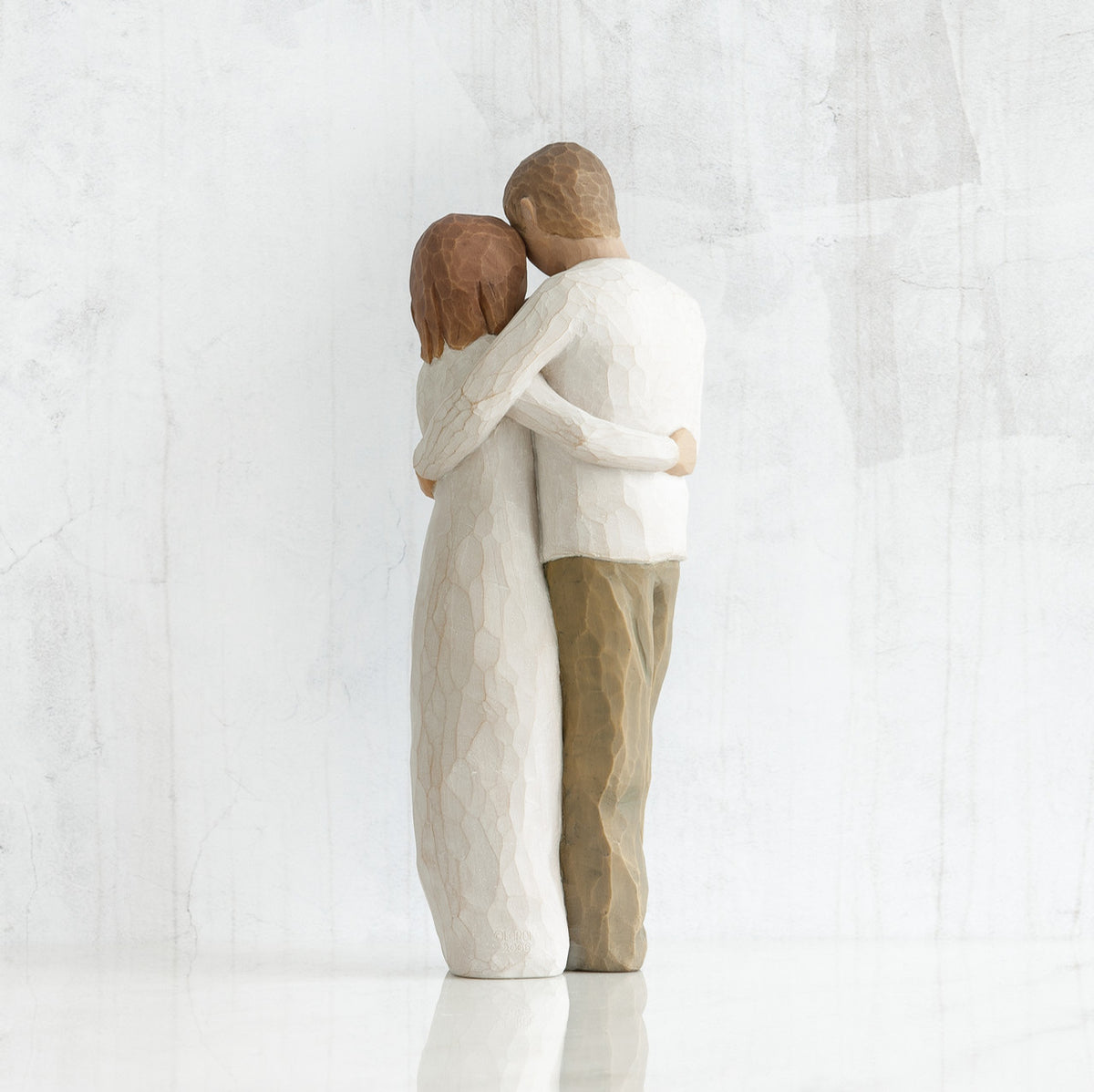 Man and woman figurines - back view - hugging another
