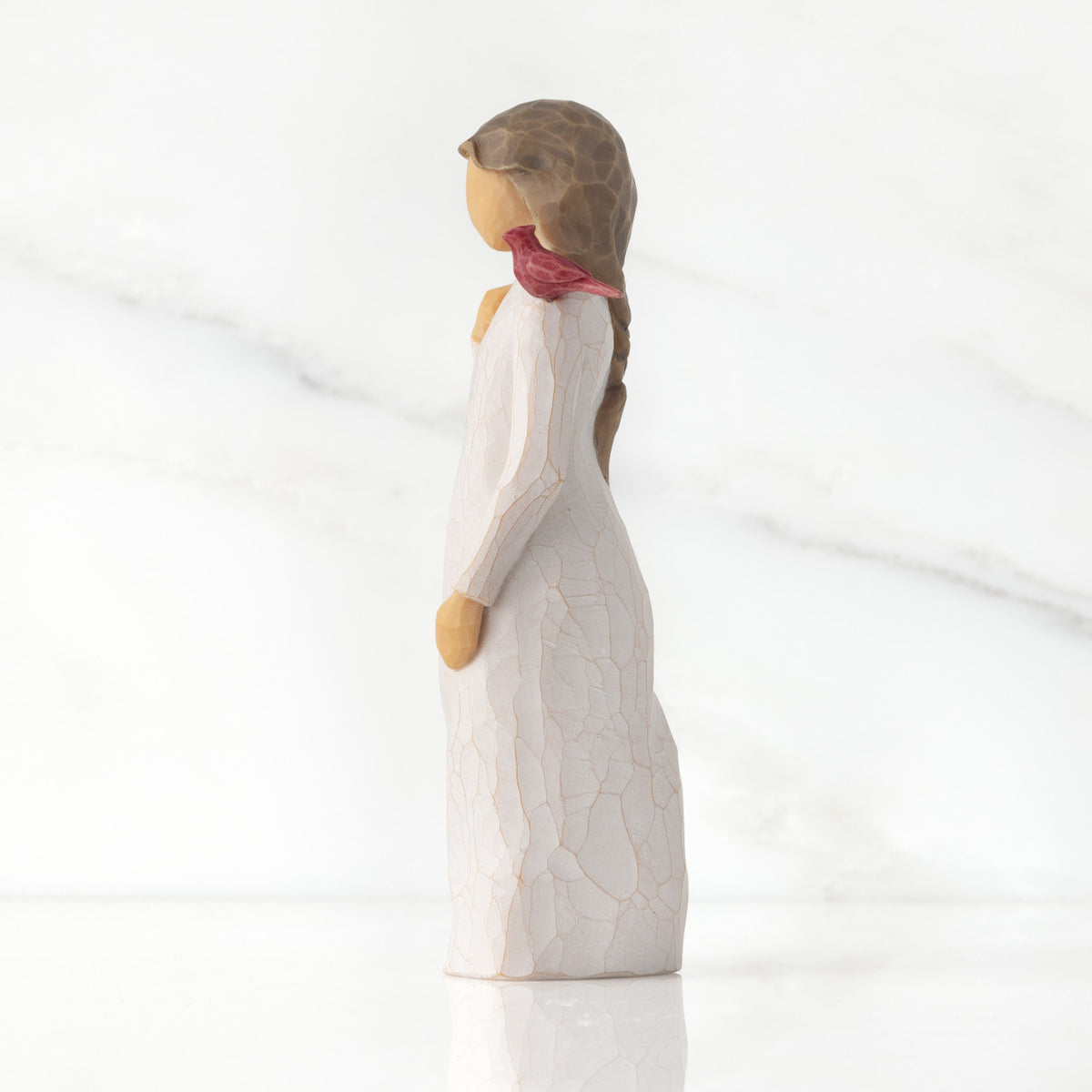 Left side of standing figure in cream dress with cardinal red bird perched on shoulder