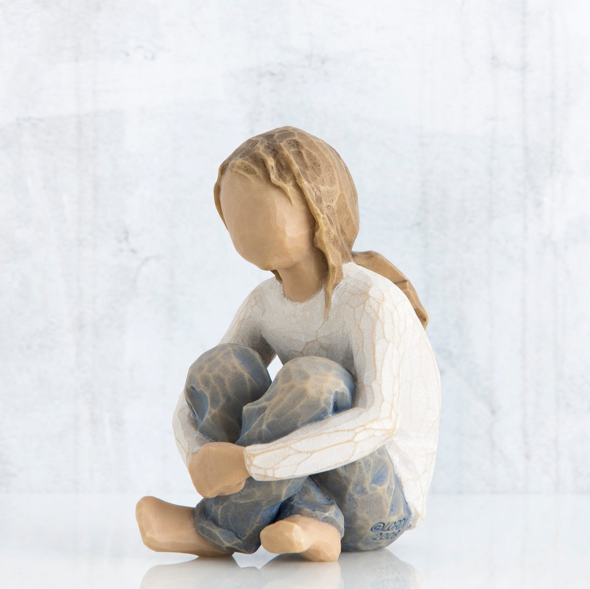 Front view of brunette girl figurine sitting down wearing white shirt and jeans