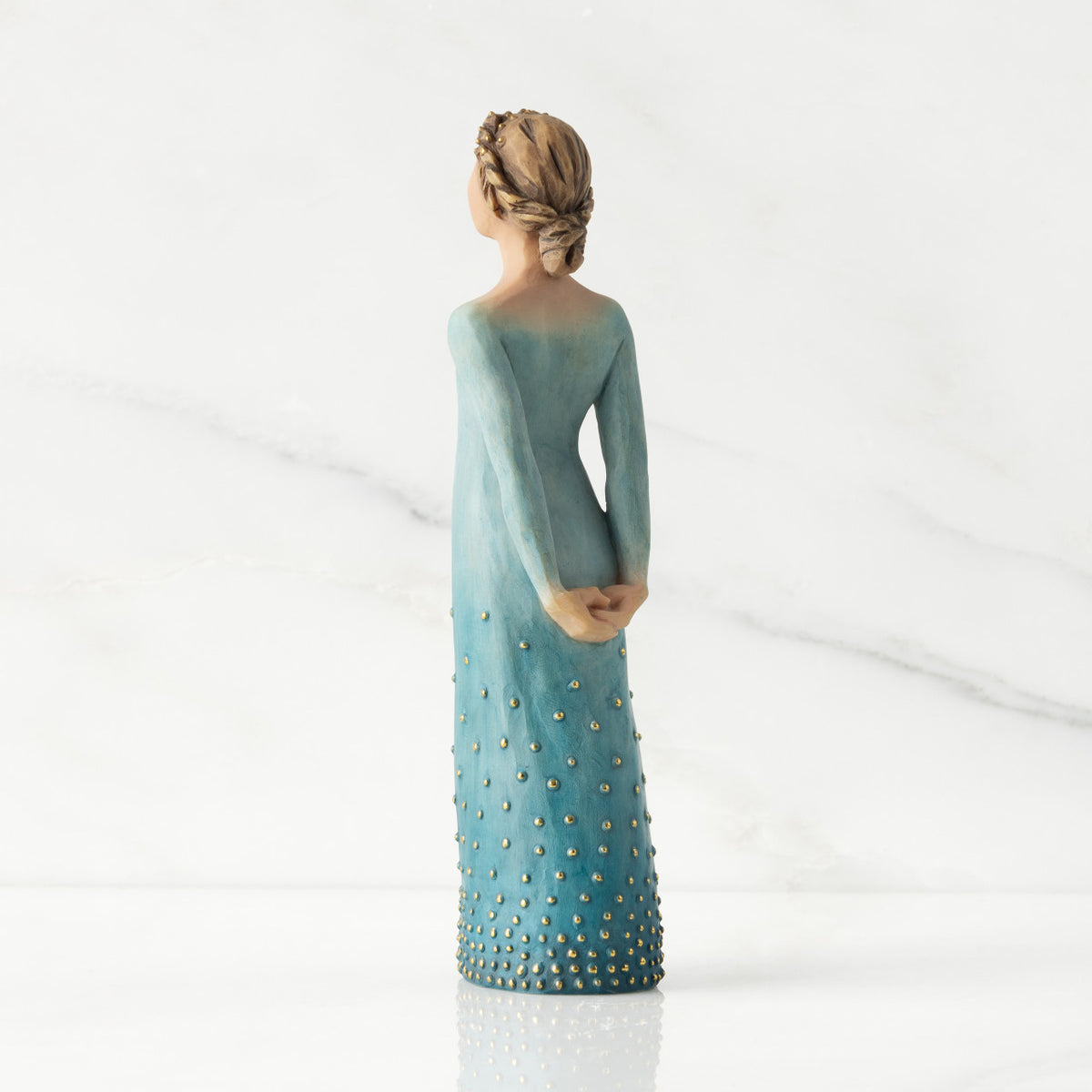 Facing left/back view: Lighter-skin figure, arms clasped behind back, hair and deep blue ombré garment dotted with gold leaf