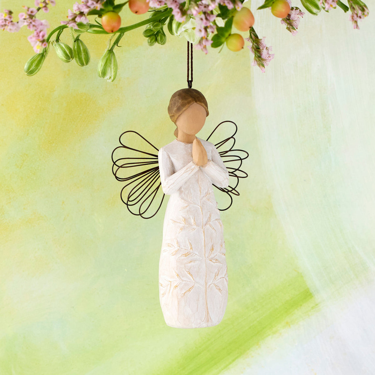 Willow Tree a tree, a prayer Ornament, 4”h hand-painted resin angel figure in cream dress with wire wings, hands in prayer position, tree carving on dress, brown elastic cord, hanging in front of lime painting