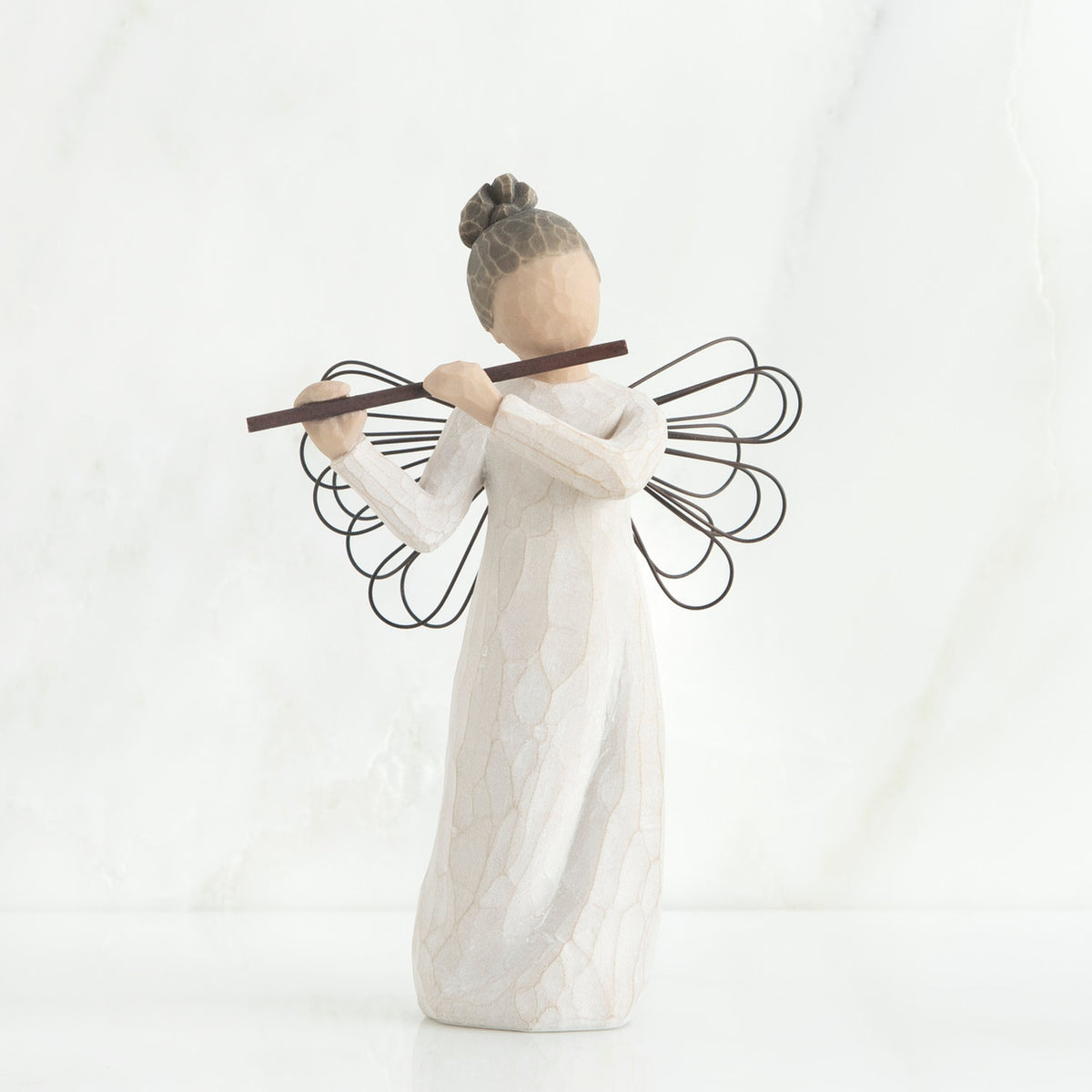 Faceless angel figurine wearing white dress and black wire wings playing black flute
