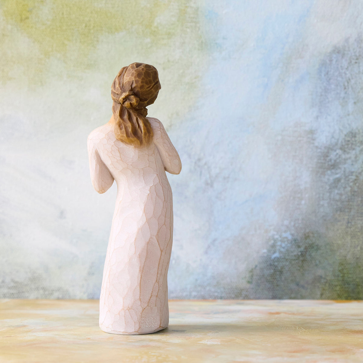 Willow Tree Here for You, back view of 5”h hand-painted standing figure in cream dress, hands to heart in empathetic gesture, in front of blue-green painting