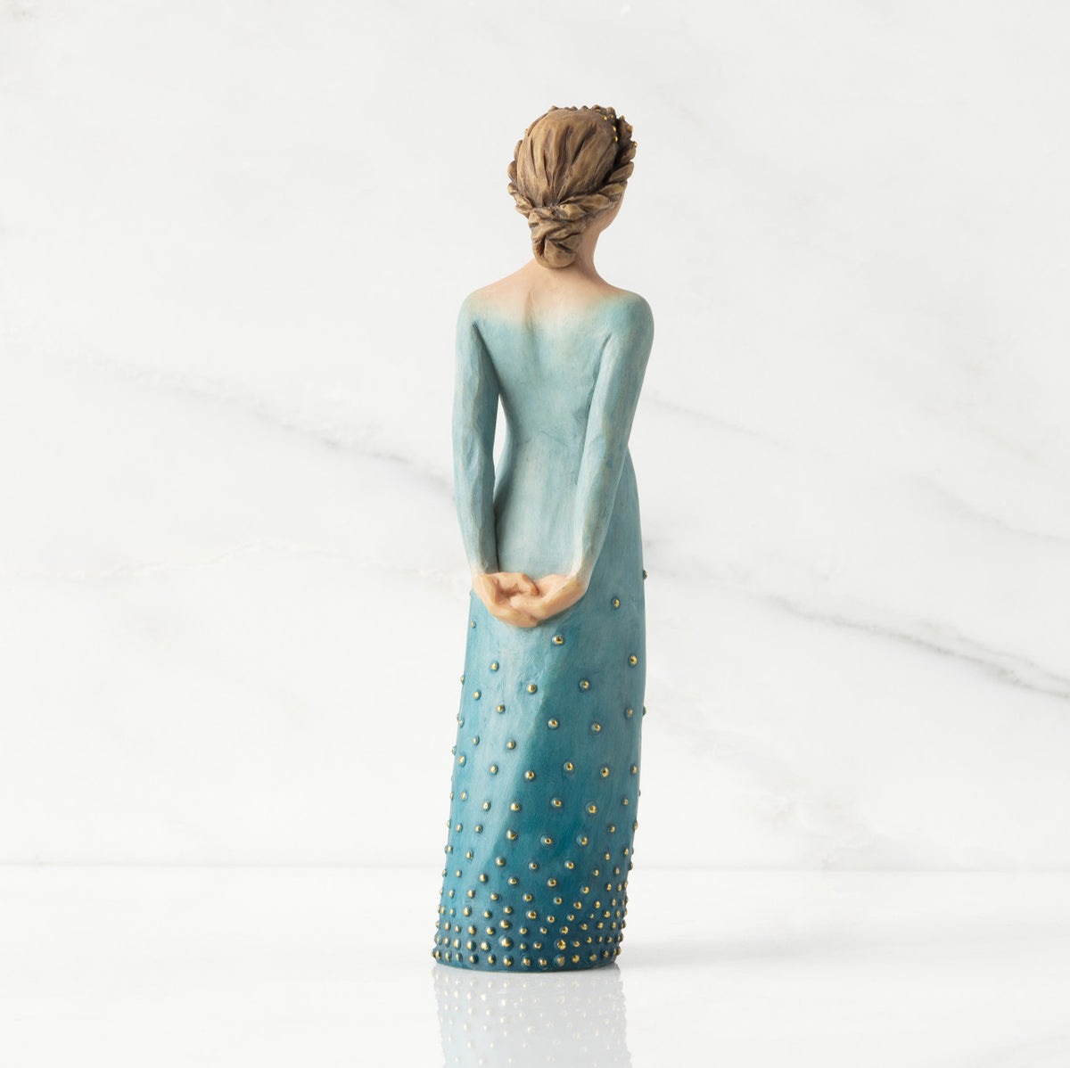 Facing back/right: Lighter-skin figure, arms clasped behind back, hair and deep blue ombré garment dotted with gold leaf